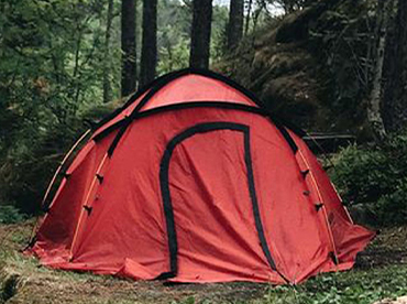 Red tent in camping site in a lush forest