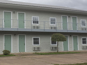 Outside view of motel with light-colored green walls with a darker green doors