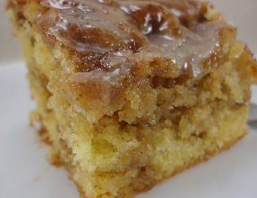 Piece of bread pudding with sweet glaze on top served on a white plate